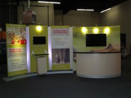 Custom 10 x 20 Exhibit with Large Format Pillowcase Graphics, Closet Storage, Reception Counter, and Pedestal. Re-configures to 10 x 10 -- Image 1