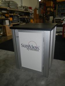 RENTAL:  RE-2008 10' x 20' Design with Arch Canopy, Double-Sided Kiosk using RE-1227 Small Rectangular Counters with Locking Doors & Interior Shelves -- Image 4